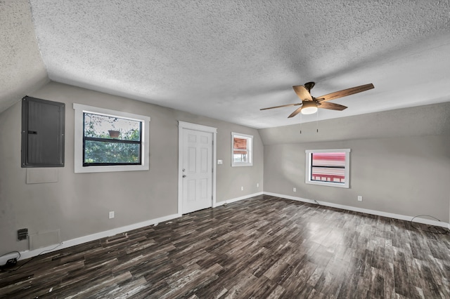 unfurnished room featuring vaulted ceiling, dark hardwood / wood-style flooring, electric panel, a textured ceiling, and ceiling fan