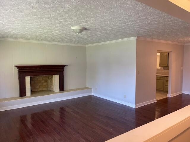 unfurnished living room with ornamental molding, a textured ceiling, and dark wood-type flooring