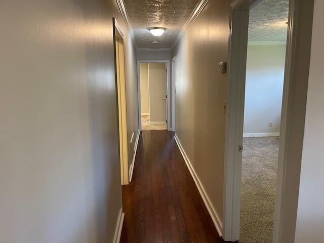 corridor featuring ornamental molding, a textured ceiling, and dark hardwood / wood-style floors