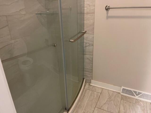 bathroom with a shower with shower door and toilet