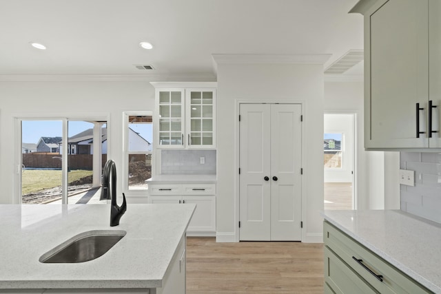 kitchen featuring light stone counters, ornamental molding, sink, and decorative backsplash