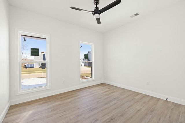 spare room with plenty of natural light, ceiling fan, and light wood-type flooring