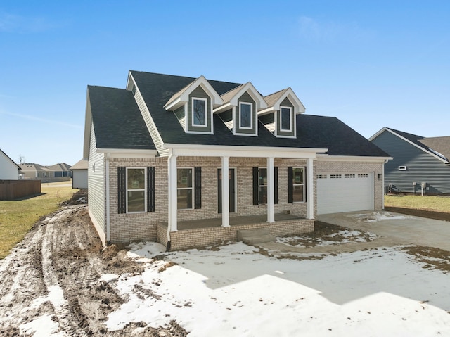 cape cod-style house featuring a garage and covered porch