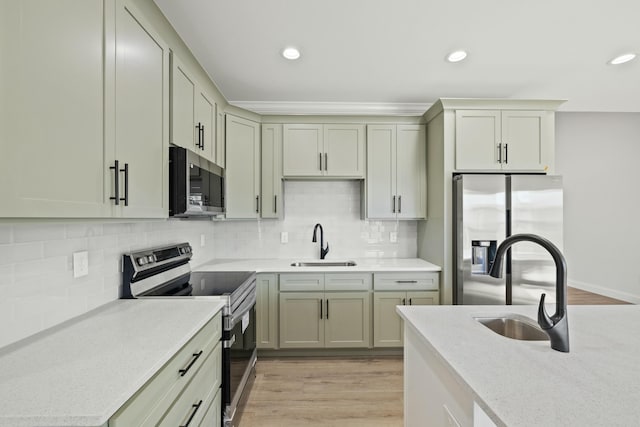 kitchen featuring sink, backsplash, light hardwood / wood-style flooring, and appliances with stainless steel finishes