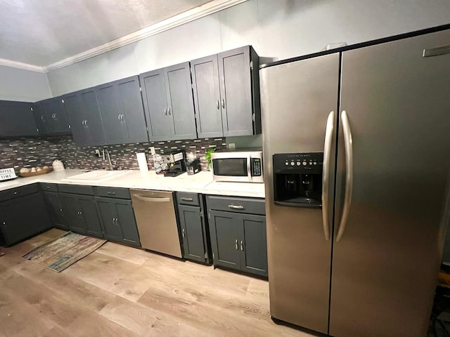 kitchen featuring light hardwood / wood-style flooring, ornamental molding, sink, appliances with stainless steel finishes, and tasteful backsplash