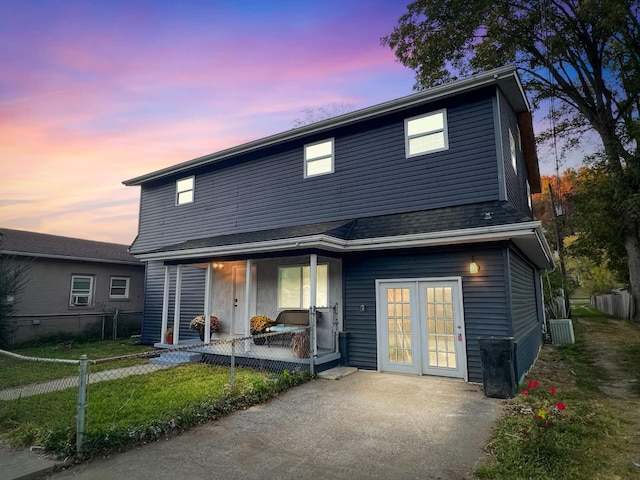 back house at dusk with a yard, central air condition unit, and a porch