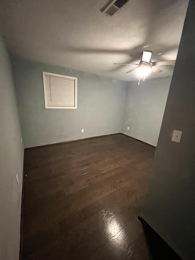 spare room with dark wood-type flooring, a textured ceiling, and ceiling fan