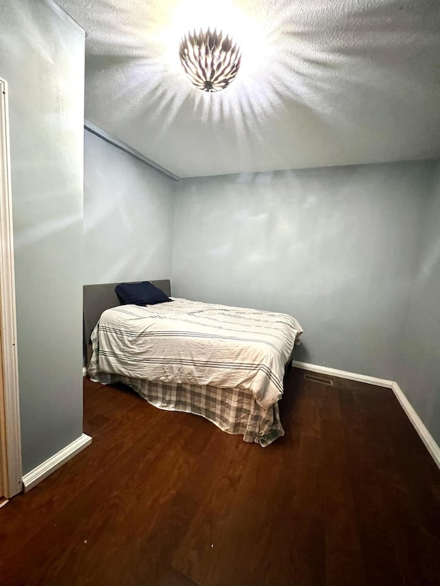 bedroom featuring a textured ceiling and dark hardwood / wood-style flooring