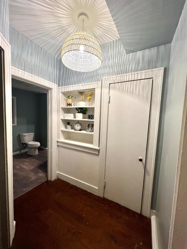 hall featuring dark wood-type flooring and a notable chandelier