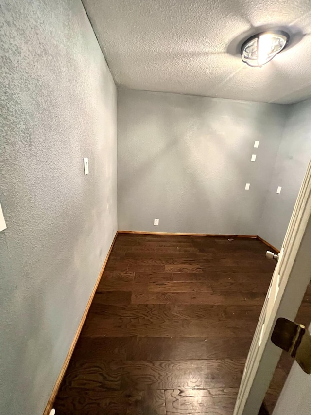 empty room with a textured ceiling and dark hardwood / wood-style floors