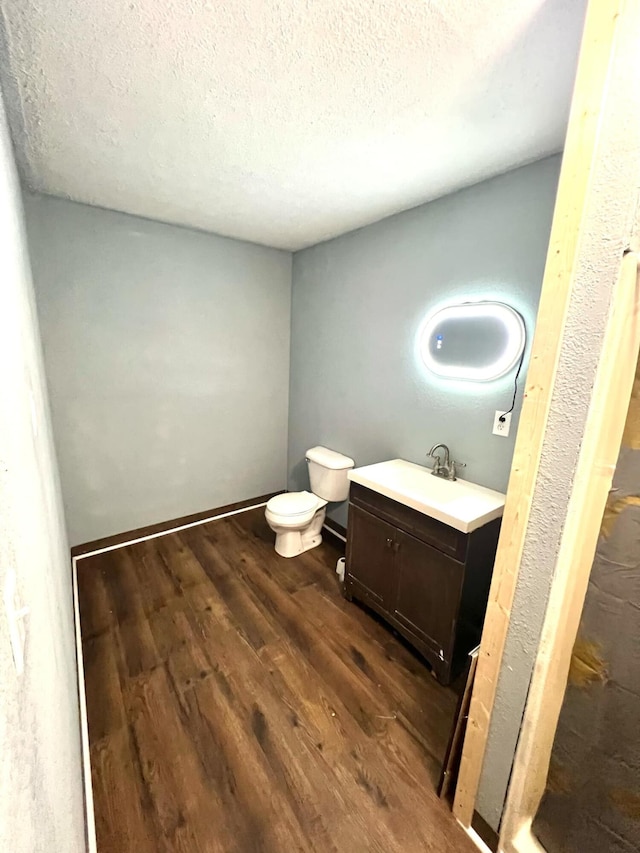 bathroom featuring vanity, a textured ceiling, toilet, and wood-type flooring