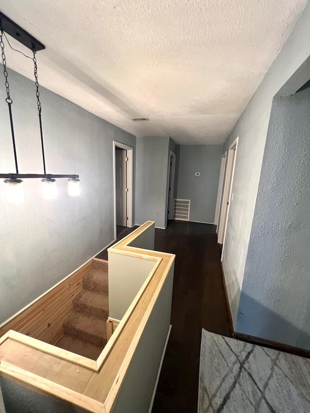 corridor featuring a textured ceiling and dark hardwood / wood-style floors