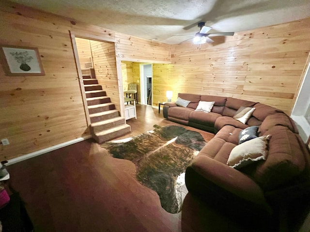 living room featuring hardwood / wood-style floors, wooden walls, and ceiling fan