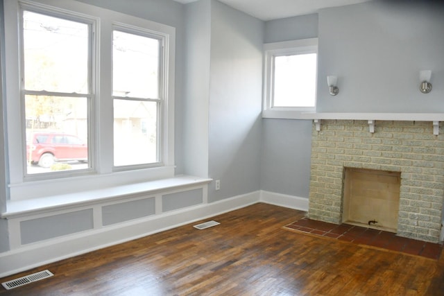 unfurnished living room featuring a brick fireplace and dark hardwood / wood-style flooring