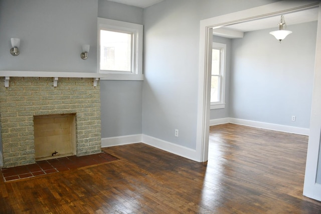 unfurnished living room featuring a wealth of natural light, a brick fireplace, and dark hardwood / wood-style flooring