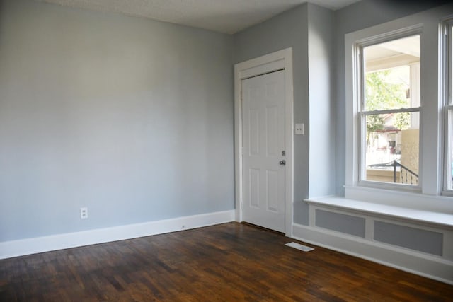 unfurnished room with dark wood-type flooring