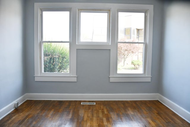 spare room with dark hardwood / wood-style floors and plenty of natural light