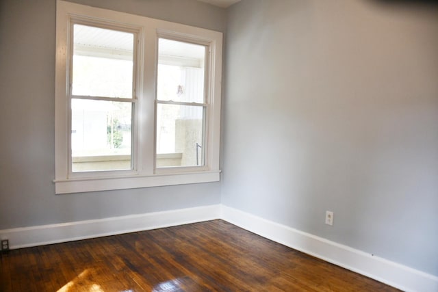 empty room featuring plenty of natural light and dark hardwood / wood-style flooring