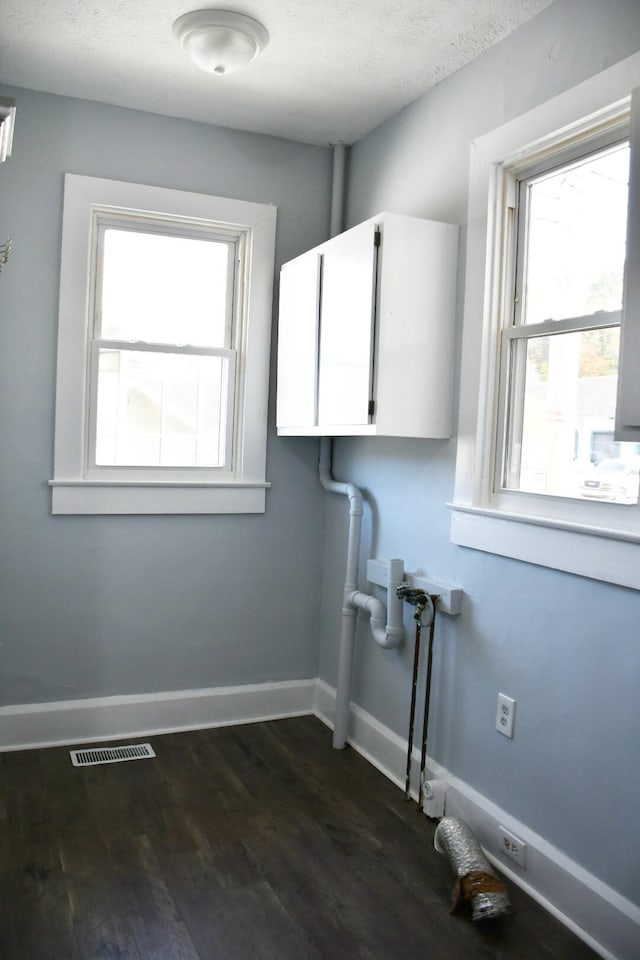 laundry room with a textured ceiling, cabinets, and dark hardwood / wood-style floors