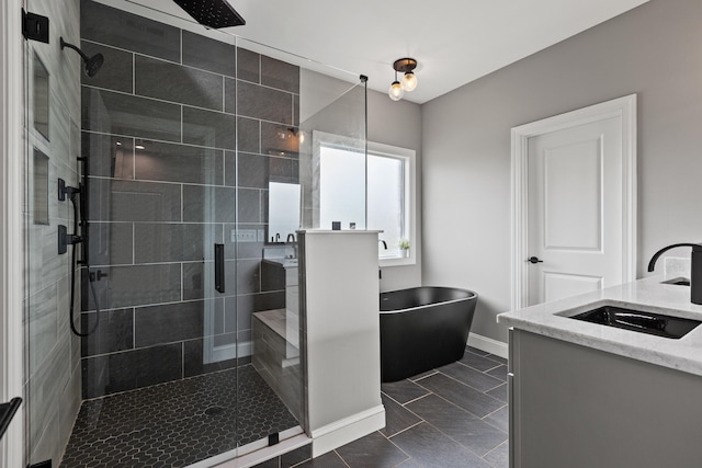 bathroom with a freestanding bath, a stall shower, vanity, baseboards, and tile patterned floors