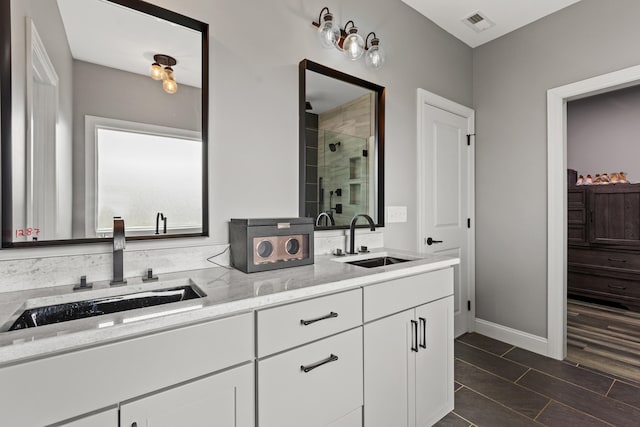 full bath with double vanity, a sink, visible vents, and a shower stall