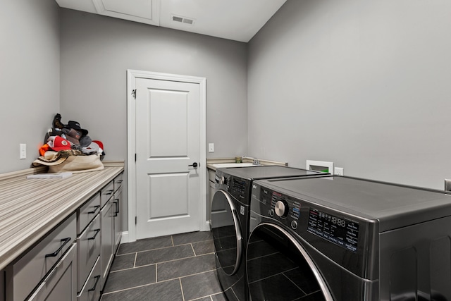 laundry room with cabinets, dark tile patterned floors, and washing machine and clothes dryer