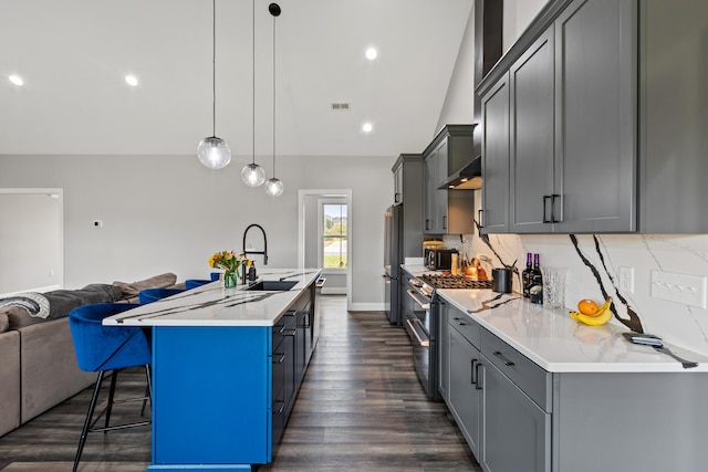 kitchen with appliances with stainless steel finishes, sink, decorative light fixtures, a breakfast bar area, and an island with sink