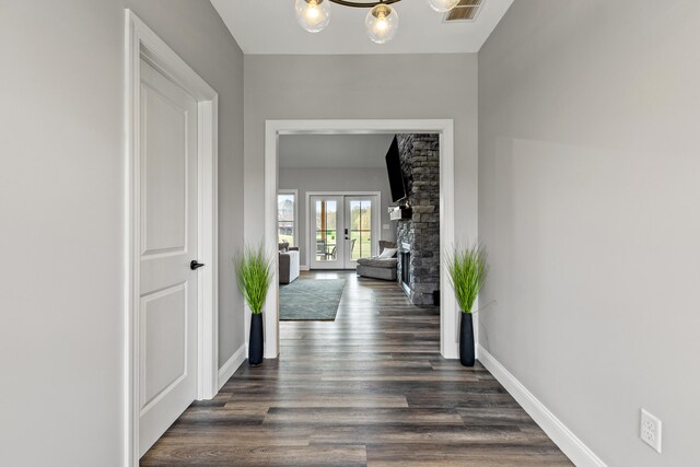 corridor featuring french doors, dark wood-type flooring, and a notable chandelier