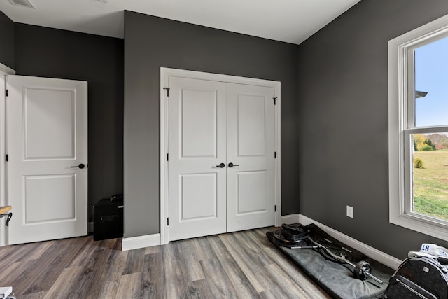 bedroom with visible vents, a closet, baseboards, and wood finished floors