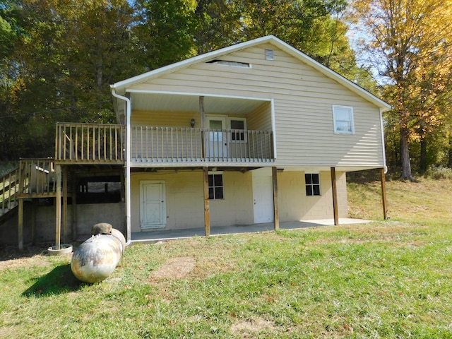 rear view of property featuring a yard, a patio, and a wooden deck