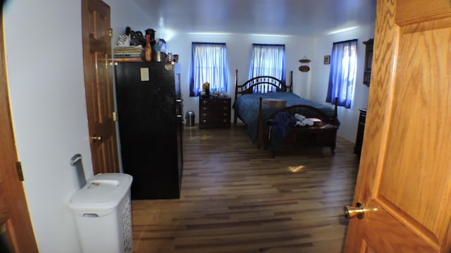 bedroom with dark hardwood / wood-style floors and black fridge