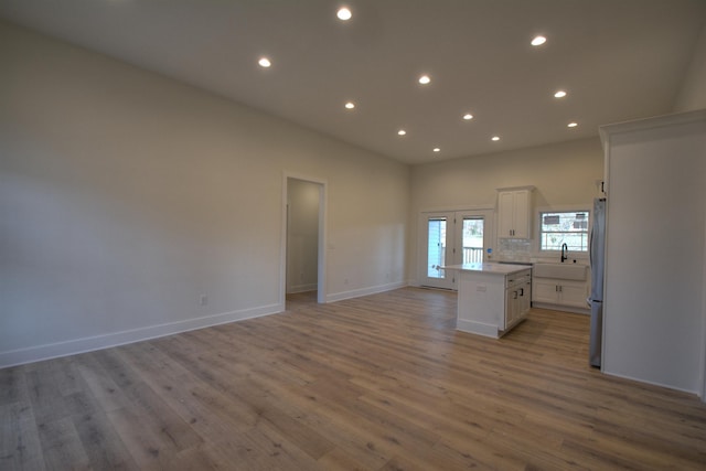 kitchen featuring stainless steel refrigerator, white cabinetry, sink, light hardwood / wood-style floors, and a kitchen island