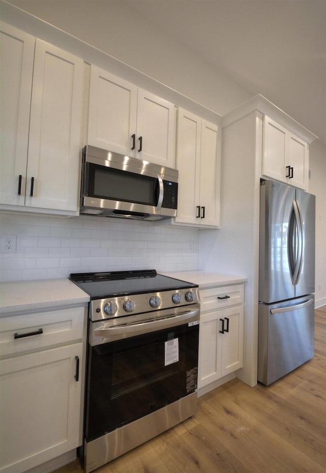 kitchen featuring white cabinets, stainless steel appliances, light hardwood / wood-style flooring, and tasteful backsplash