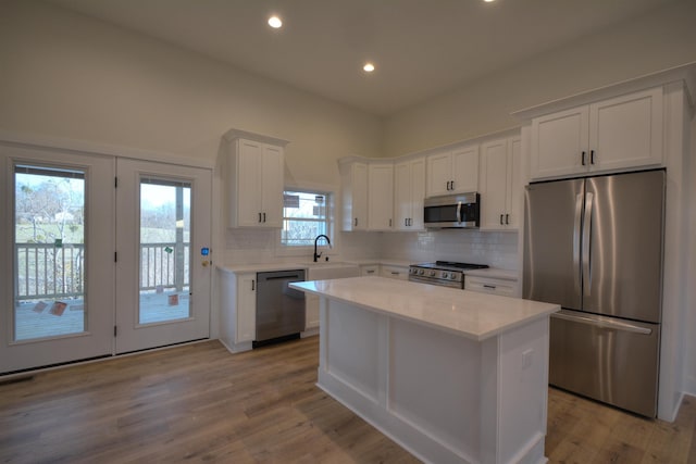 kitchen with a healthy amount of sunlight, a kitchen island, light hardwood / wood-style floors, and stainless steel appliances