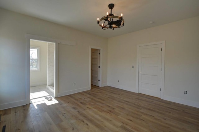 interior space featuring hardwood / wood-style flooring, ensuite bath, and a notable chandelier