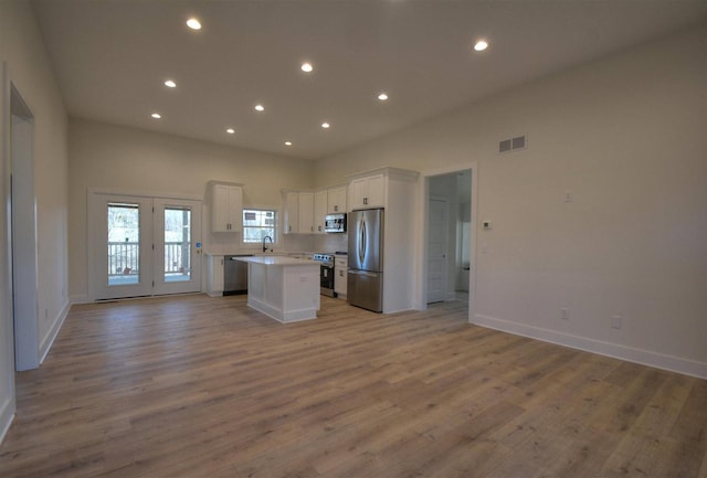 kitchen with a center island, sink, appliances with stainless steel finishes, light hardwood / wood-style floors, and white cabinetry