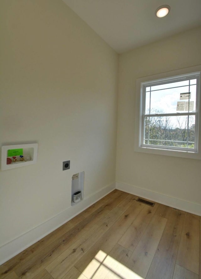 clothes washing area featuring washer hookup, light hardwood / wood-style floors, and electric dryer hookup