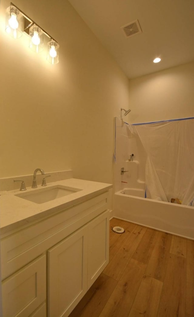 bathroom with hardwood / wood-style floors, vanity, and shower / tub combo