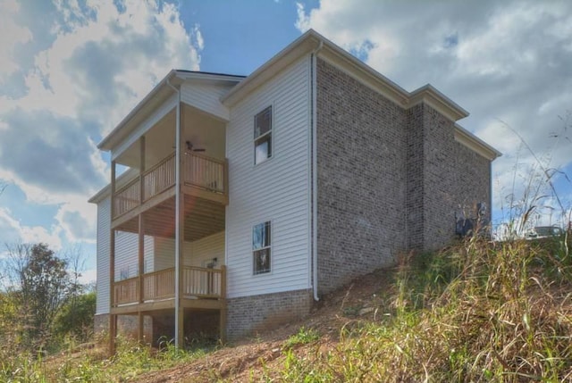 view of side of home featuring a balcony and ceiling fan