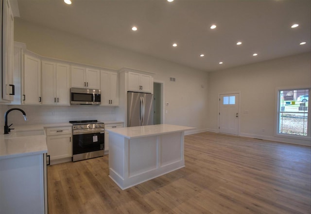 kitchen with white cabinets, appliances with stainless steel finishes, a center island, and sink