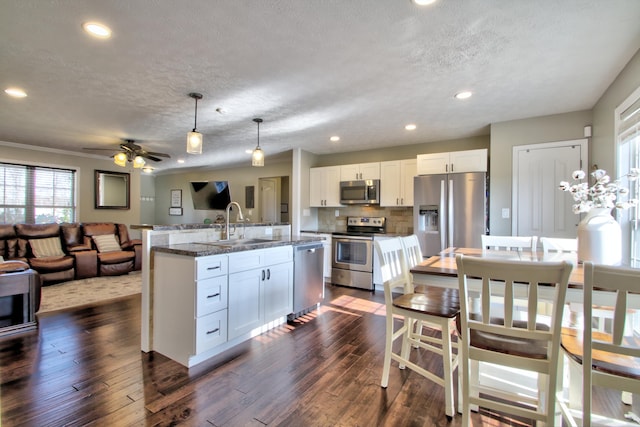 kitchen with appliances with stainless steel finishes, hanging light fixtures, dark hardwood / wood-style floors, and white cabinets