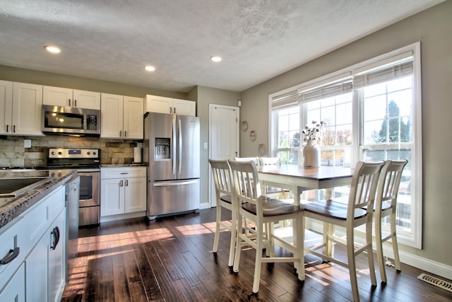 kitchen with white cabinetry, stainless steel appliances, tasteful backsplash, and dark hardwood / wood-style flooring