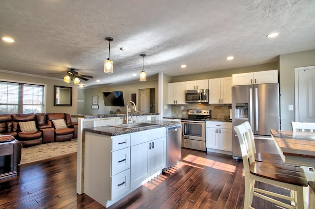 kitchen with sink, hanging light fixtures, white cabinetry, stainless steel appliances, and dark wood-type flooring