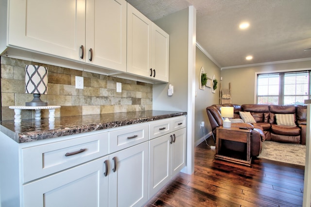 kitchen with dark stone countertops, crown molding, dark hardwood / wood-style flooring, and white cabinets