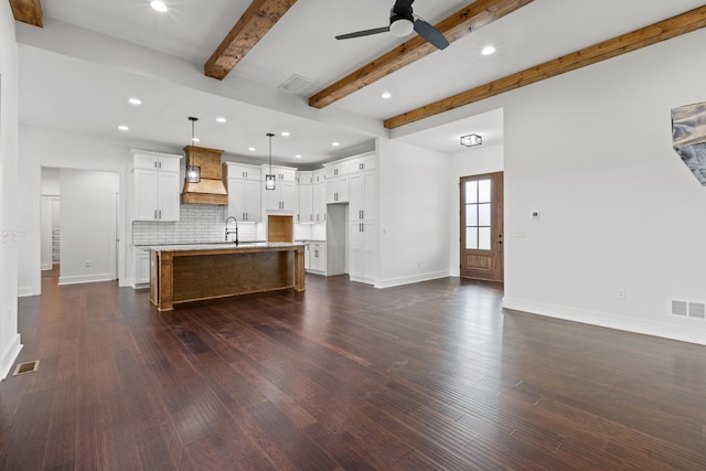 kitchen with pendant lighting, sink, a kitchen island with sink, white cabinets, and decorative backsplash