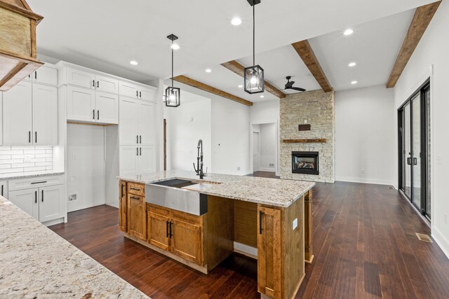 kitchen with pendant lighting, sink, an island with sink, and white cabinets