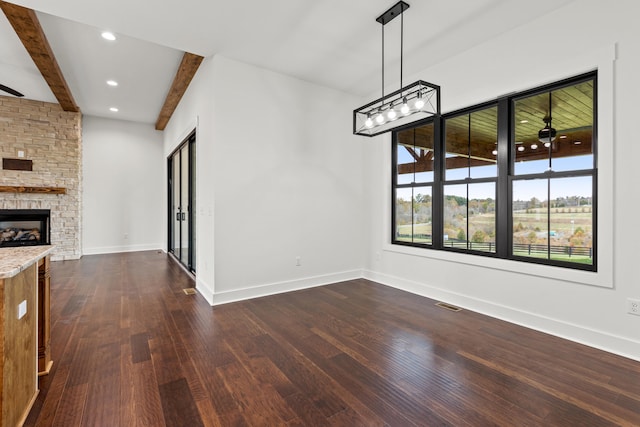 unfurnished dining area with dark wood-type flooring, a fireplace, and beam ceiling