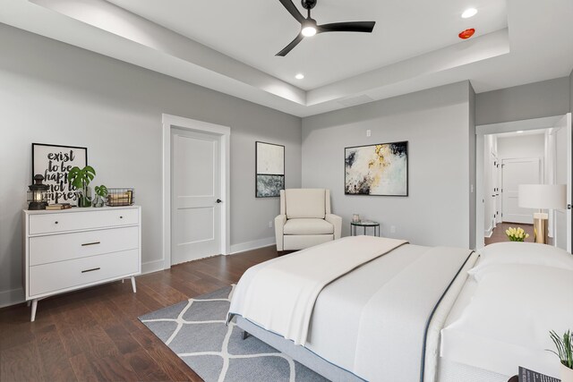 empty room featuring a raised ceiling, dark wood-type flooring, and ceiling fan