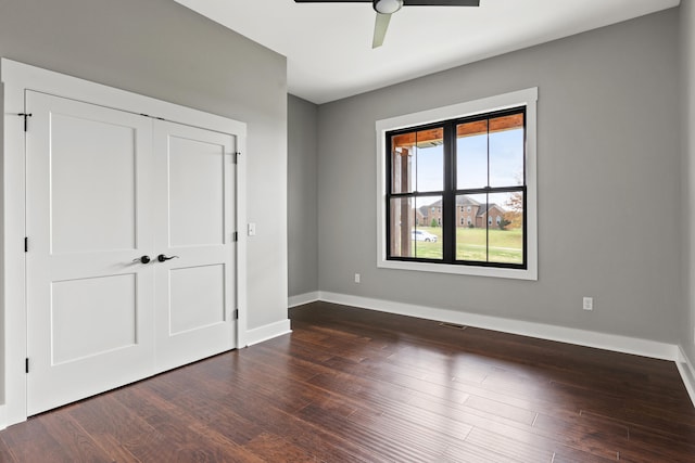 unfurnished bedroom with dark hardwood / wood-style flooring, a closet, and ceiling fan