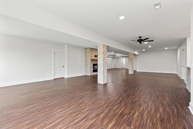 unfurnished living room featuring dark wood-type flooring, ceiling fan, and a fireplace